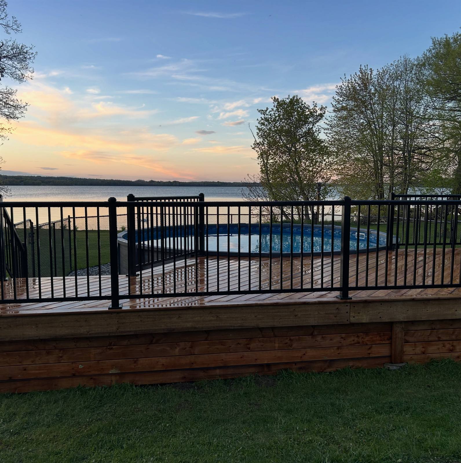 Lakeside cedar deck with black aluminum railing at sunset in the Kingston area