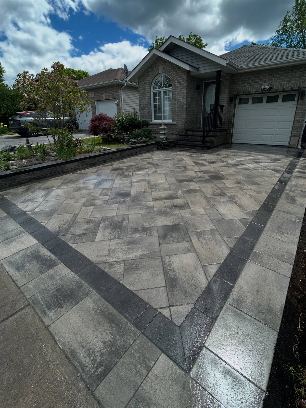 Interlock driveway with a charcoal soldier-course border installed by Gonzo Construction in Kingston, Ontario
