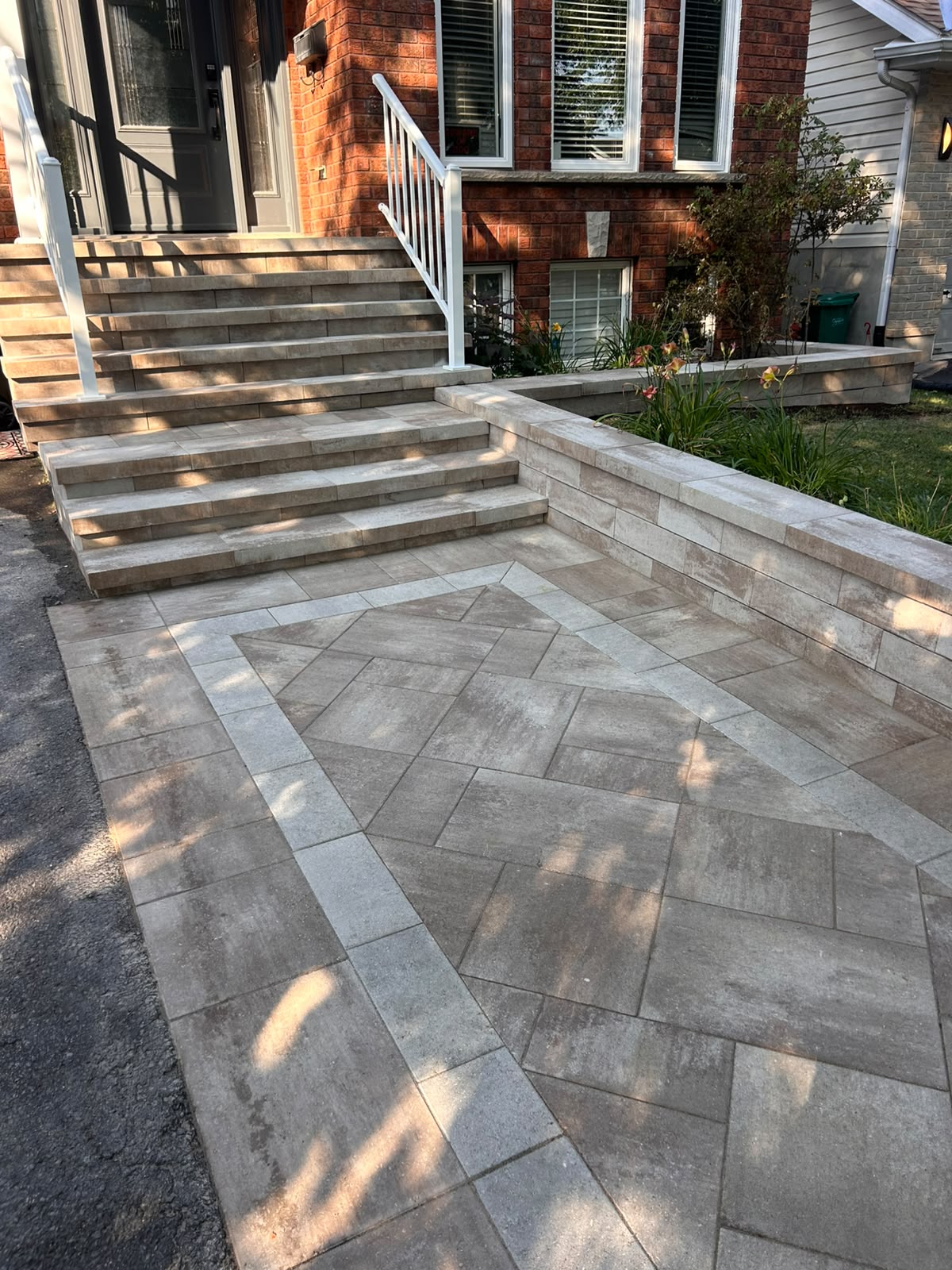 Milano-combo interlock front entrance with matching stone steps, a raised retaining wall and a banded walkway in Kingston, Ontario