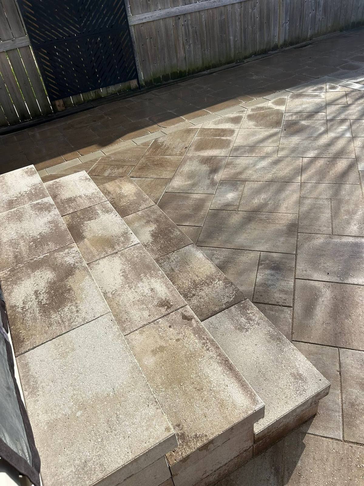 Tan interlock patio with matching stone steps and light soldier-course border in Kingston, Ontario