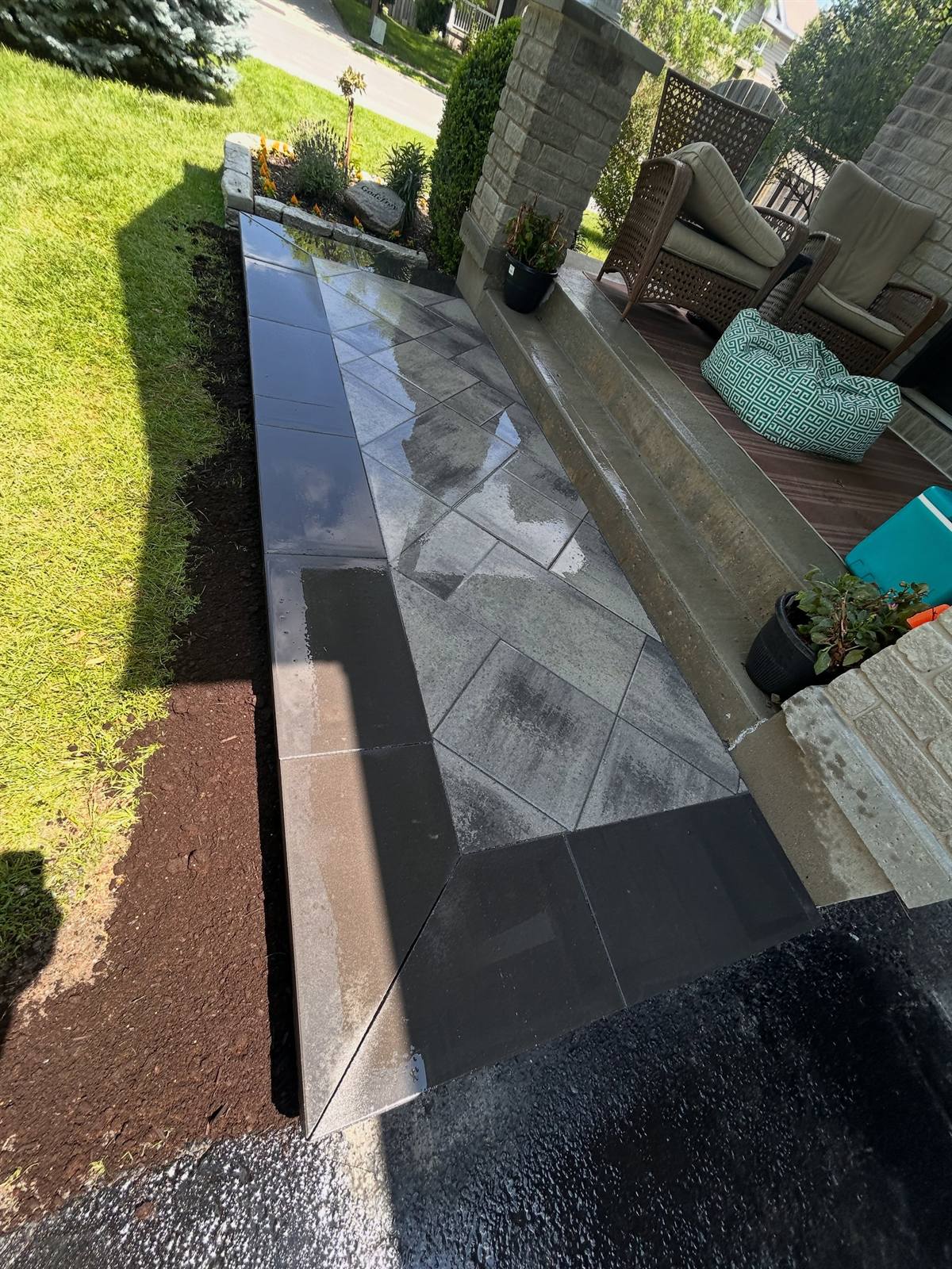 Charcoal bluestone patio landing with a black soldier-course border in Kingston, Ontario